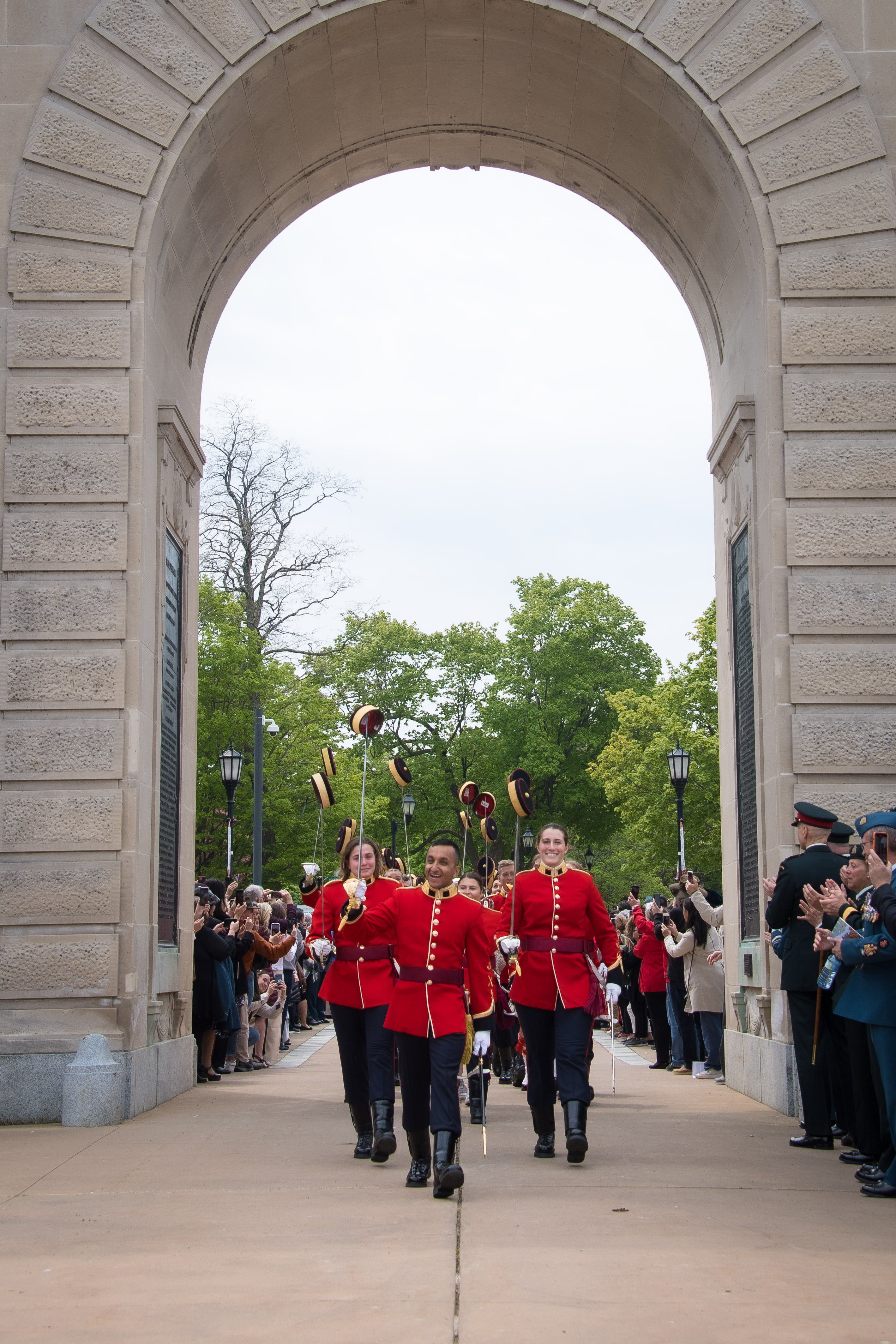 The Cadet Wing Commander leading the procession of graduating Fourth-Year cadets marching under the Memorial Arch on campus while the public look on.